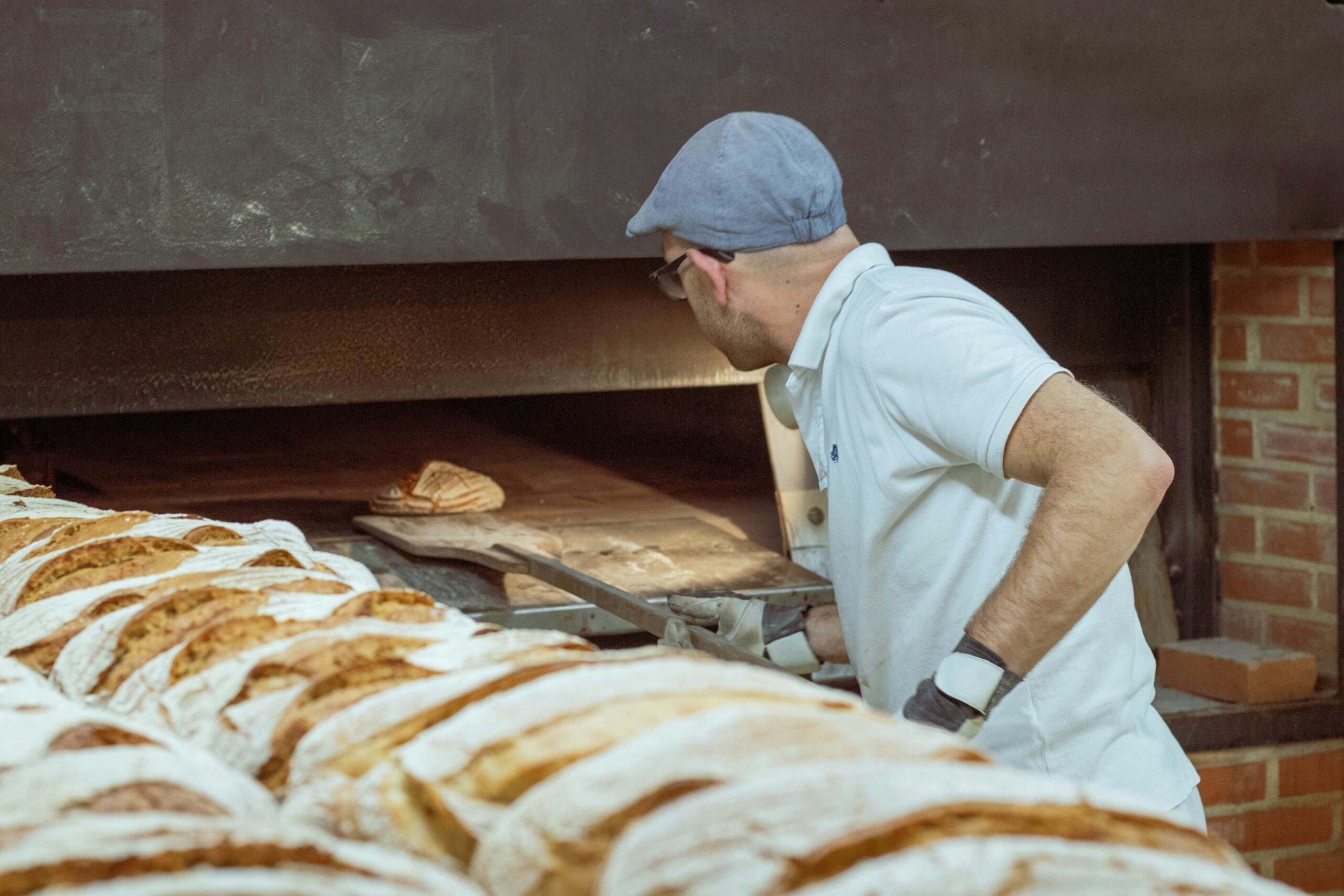 Gentlemen taking bread out of a brick over with a pizza spatula.